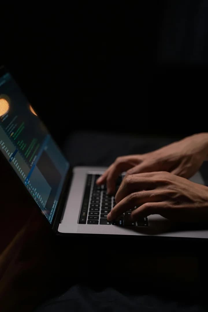 Professionista che studia certificazioni cybersecurity su laptop in ambiente scuro