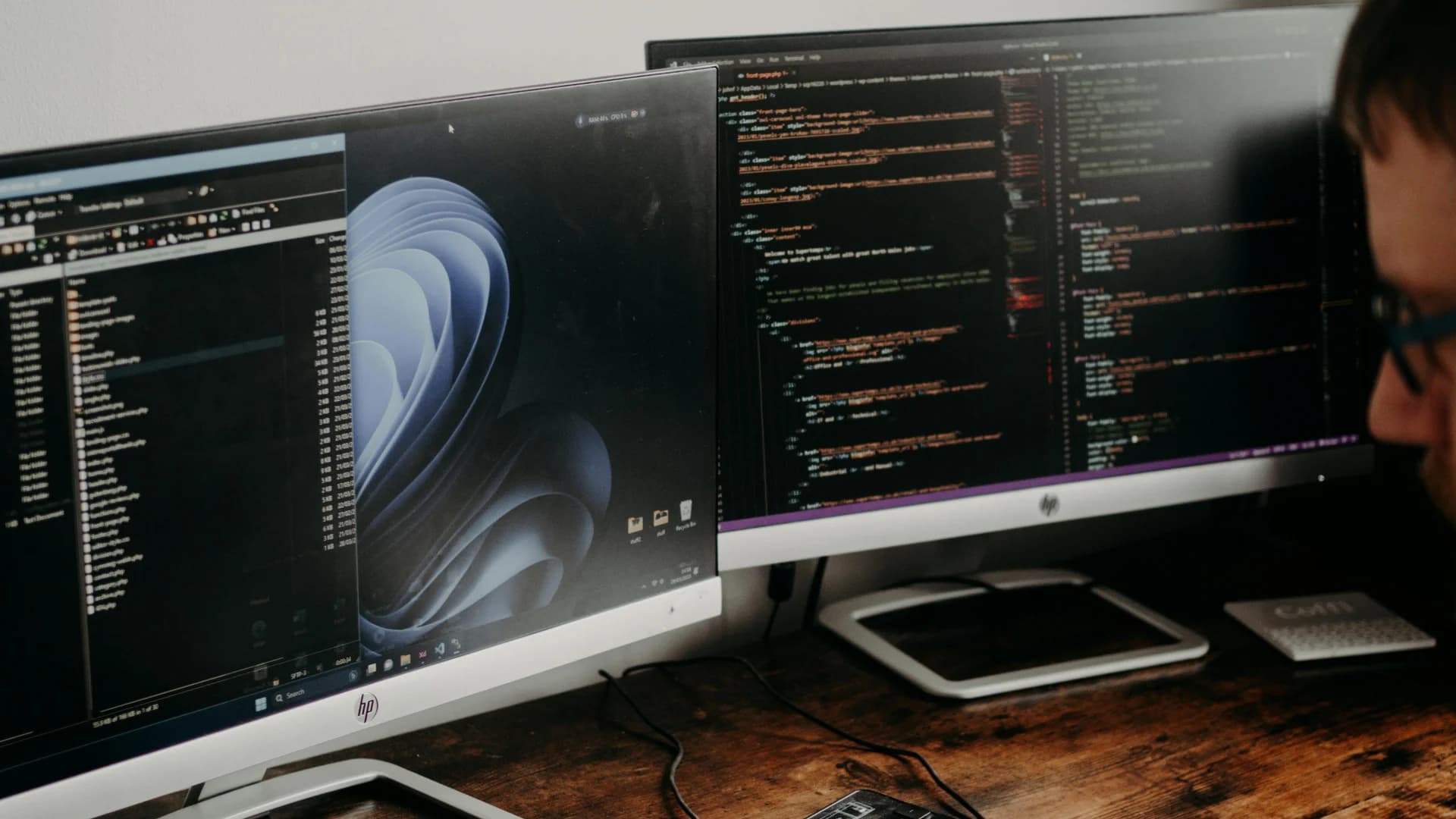 Analista di sicurezza alla postazione di lavoro con più monitor che mostrano codice e dashboard di sicurezza