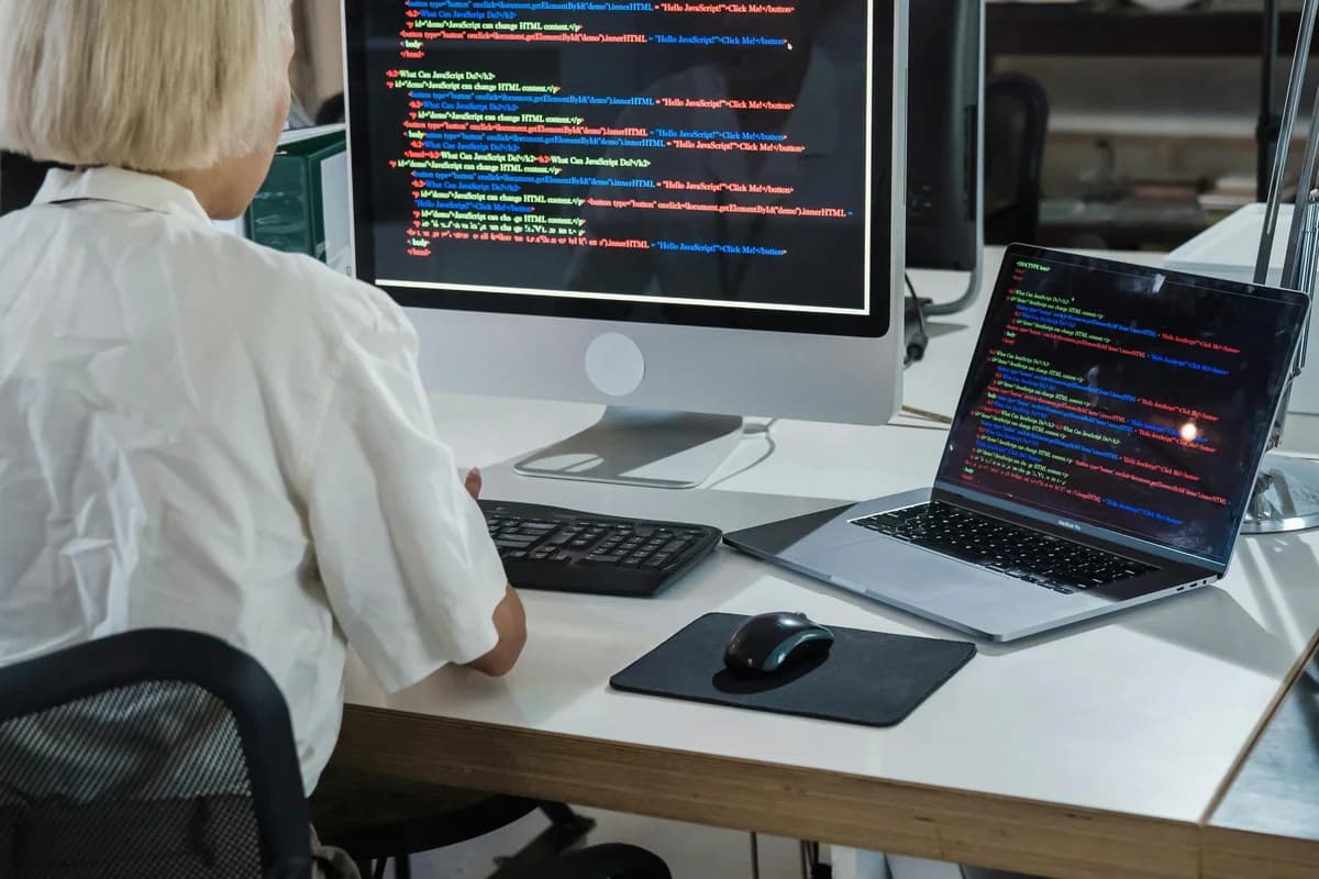 Postazione professionale di analista di sicurezza con più monitor che mostrano codice